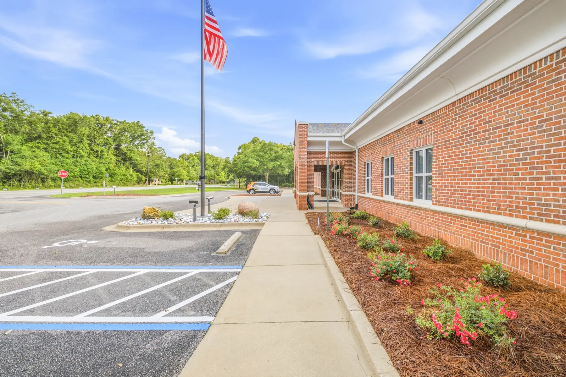Brick side elevation, flagpole, walkway and landscaped beds at Cadenhead Legacy Center in Pace, Florida